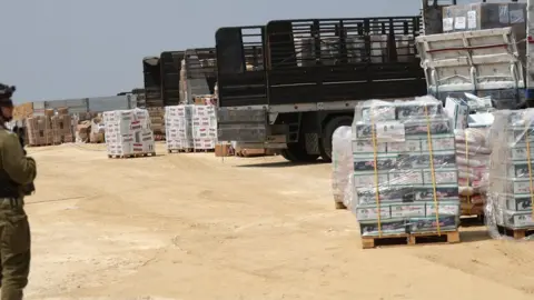 EPA-EFE/REX/Shutterstock An Israeli soldier keeps watch as aid lorries to Gaza are checked at the Erez Crossing. Photo: 1 May 2024