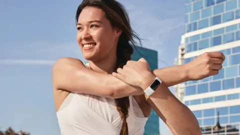 A woman exercises wearing a fitbit charge 5