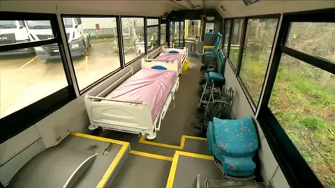 Hospital beds in bus replacing the chairs.