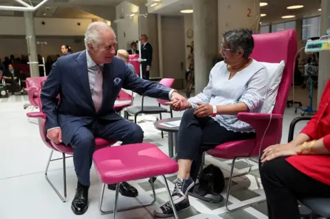 PA Media Charles holds hands with cancer patient Asha Millan