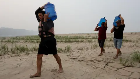 People carry drinking water along a sandbank of Madeira River in Paraizinho Community, in Humaita, Amazonas state, northern Brazil, on September 7, 2024.