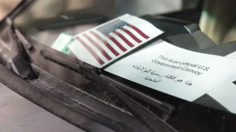 Getty Images A car belonging to the US delegation parked outside a hotel in Damascus. On the dashboard a US flag and government sign is displayed