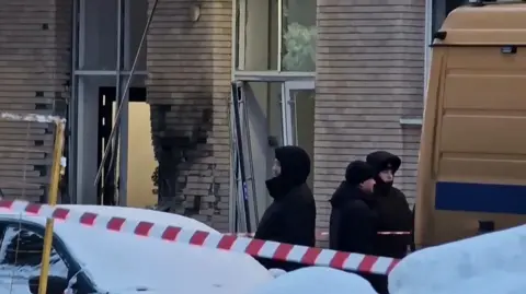 Men guard a building with a blackened window in Moscow