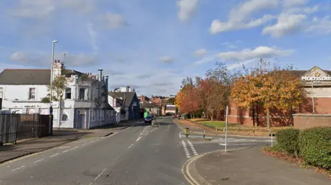 A view of Cattle Market Road heading towards South Bridge on Google streetview. There is a white building on the right and a Morrisons supermarket on the left. 