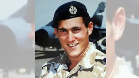 Gideon Amos Office Mark Shephard - a smiling man in uniform looking at camera with military aircraft in the background 