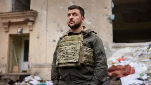 Getty Images President Zelensky stood in front of a bombed-out building. 