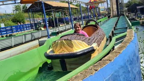 Phoebe Bates sat on the Flambards log flume during a sunny day. She is wearing a pink t-shirt and has just been soaked from the flume.