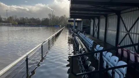 A row of seats in a metal shed at Lydney Town football club's pitch, which is totally flooded