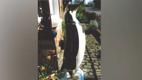 Julia Giles A four foot-high penguin decoration on a plinth in the front garden of a house.