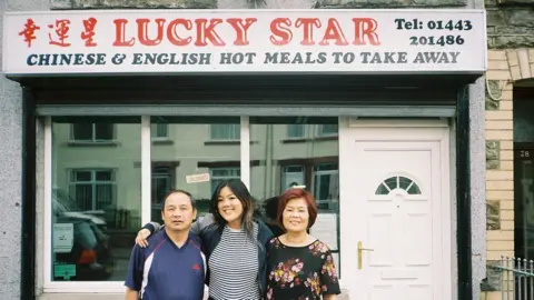 Angela Hui Angela and her parents in 2018 outside the takeaway after her last day of service.