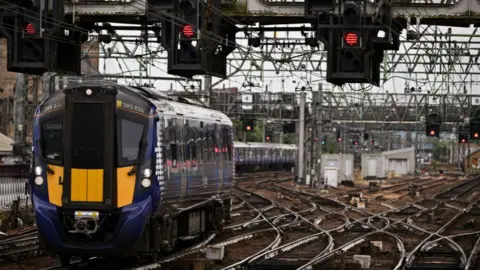 A train pulls into Glasgow Central station underneath three red lights 