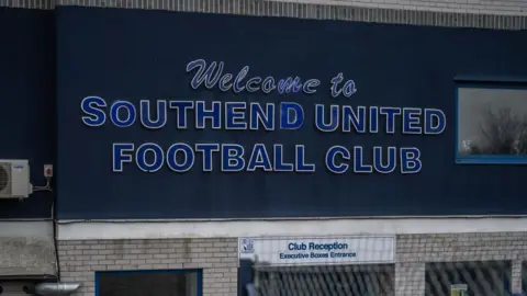 A large sign for Southend United Football Club fitted above the club reception at Roots Hall stadium.