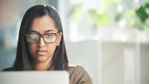 A young woman working on a laptop in an office