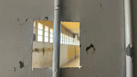 A square opening in the centre of the metal door of a cell in Saydnaya prison