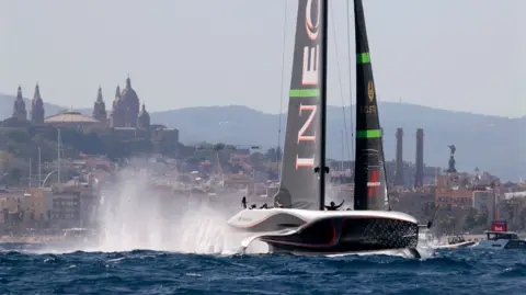 An America's Cup boat sends up spray into the air as it races off the Barcelona coast.