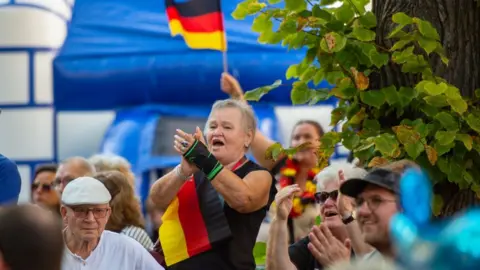 Woman claps at rally with German flag