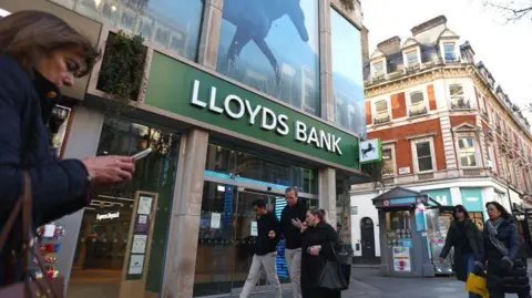 People walk past a branch of Lloyds Bank on Oxford street on January 26, 2024 in London, England.