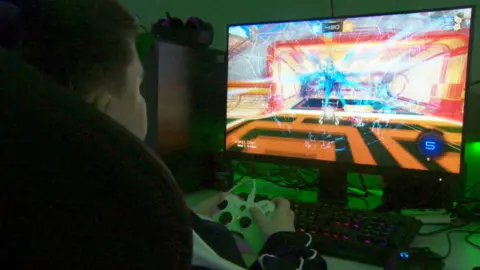 Boy playing esports, large computer game screen