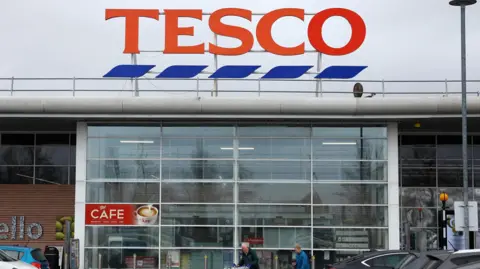 Shoppers are seen leaving a Tesco store