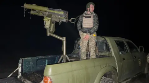 BBC/James Cheyne The witches - with a male colleague - mount their machine gun during the night op