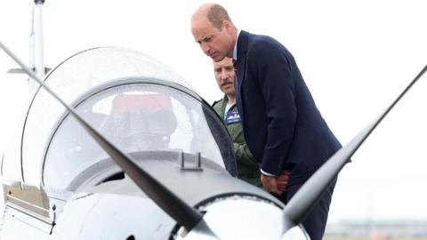 The Prince of Wales, Royal Honorary Air Commodore, RAF Valley, (right) gets an introduction to a RAF Short Tucano trainer aircraft during a visit to the RAF Valley airbase in Anglesey