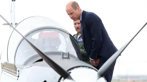 PA Media The Prince of Wales, Royal Honorary Air Commodore, RAF Valley, (right) gets an introduction to a RAF Short Tucano trainer aircraft during a visit to the RAF Valley airbase in Anglesey