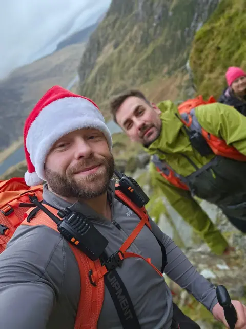 David Glyn Jones Mr Jones (left) pictured, has a thick mousy brown beard and is wearing a christmas hat. Mr Churchward (right) wears a green rainmac, orange backpack, has dark hair and stubble. 