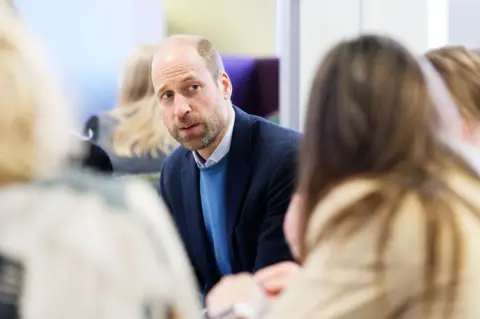 PA Media Prince Wililam, wearing a light blue jumper and darker jacket, is seen speaking to a group of women 