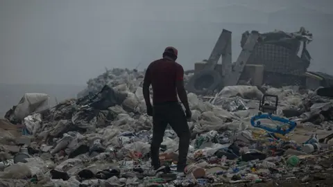 Man standing over pile of rubbish