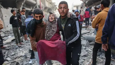 An injured woman is evacuated after an Israeli strike in Gaza City's Sabra neighbourhood, northern Gaza (3 December 2024)