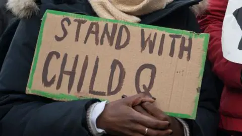 Image of woman holding sign saying: "stand with Child Q"