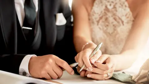 Couple sign wedding certificate, marriage registration and document paper for legal union. Closeup bride, groom and hands writing contract for celebration of love, commitment and agreement together