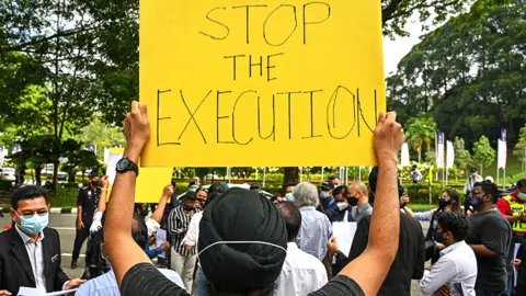 AFP An activist holds a placard before submitting a memorandum to parliament in protest at the impending execution of Nagaenthran K. Dharmalingam, sentenced to death for trafficking heroin into Singapore, in Kuala Lumpur on November 3, 2021