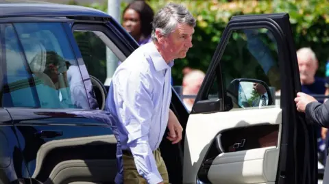 PA Vice Admiral Sir Tim Laurence arriving at Southmead Hospital in Bristol. He is seen stepping out of a jeep car and is wearing a shirt with no tie. 