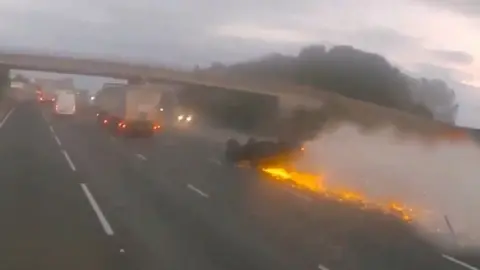 Car sliding along on its roof with sparks coming out of it after it was rammed from behind by a drink driver.