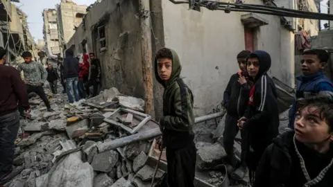 EPA-EFE Palestinians inspect the rubble of destroyed buildings following Israeli airstrikes on Nuseirat refugee camp in Gaza (07/12/24)