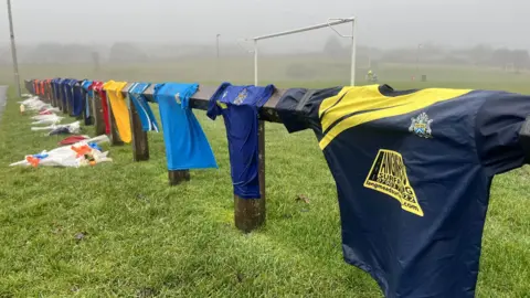 Football shirts and flowers laid out on field in tribute