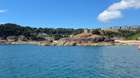 Janvrin's Tomb in Portelet Bay in Jersey. A tomb on a rocky shore and surrounded by calm sea