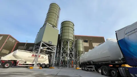 A picture of Material Evolution's factory in Wrexham, also showing a mixing tower and industrial vehicles