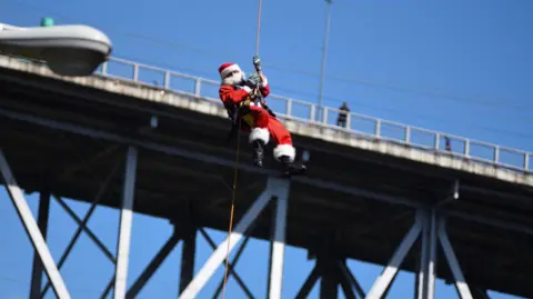 Hector Chacon dressed as Santa Claus abseiling down a bridge in Guatemala City.