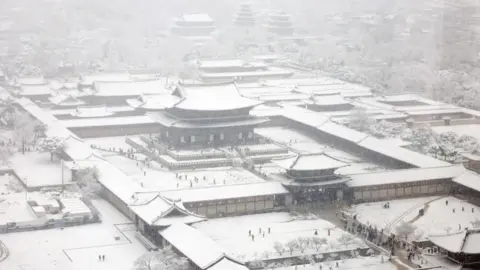 EPA-EFE/REX/Shutterstock Gyeongbokgung Palace is blanketed with snow amid a heavy snow alert in downtown Seoul, South Korea.