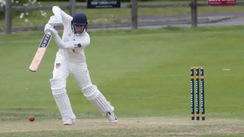 Cricketer batting and playing  a front-foot shot