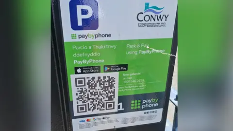 A Conwy council parking machine with a fake QR code in the bottom left corner