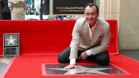 Jude Law takes a picture with his star.