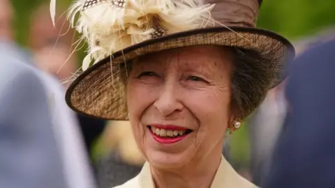 PA Princess Anne in a yellow hat with feathers on it. 