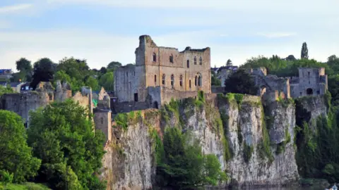 A view of Chepstow Castle from across the Wye river at sunset.