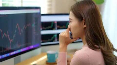 Woman looks at financial data on a number of computer screens