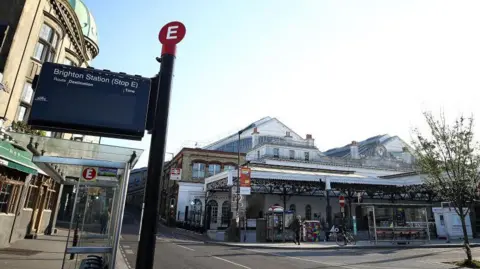 A picture of Brighton Station's entrance, with a bus stop sign in the foreground