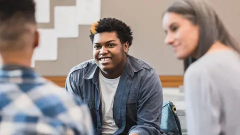 An image showing a young person speaking with adults  