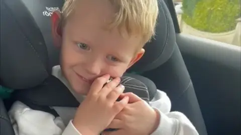 Thomas cuddles teddy bear with hearing aids